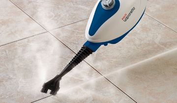 L'image montre le Polti Vaporetto SV210 nettoyant les joints de carrelage à la vapeur en mode nettoyeur portable