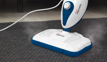 La photo montre le Polti Vaporetto SV210 nettoyant un tapis gris à la vapeur