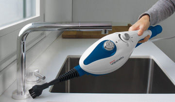 L'image montre le Polti Vaporetto SV210 nettoyant un évier en mode nettoyeur portable