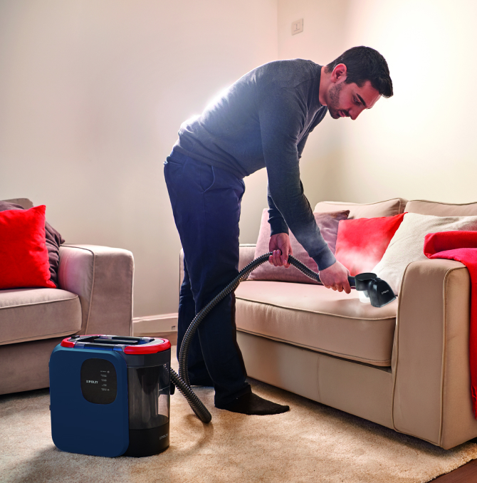 un homme nettoyant un canapé à la vapeur