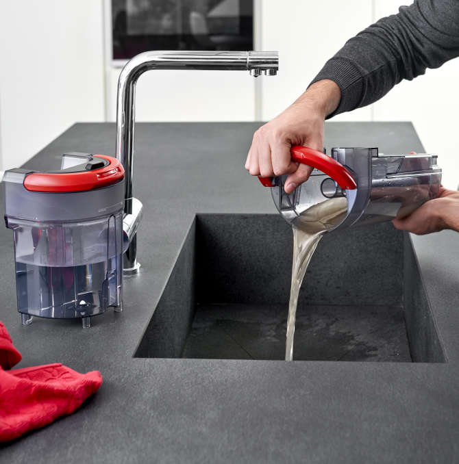 un homme jetant un réservoir d'eau sale dans un évier